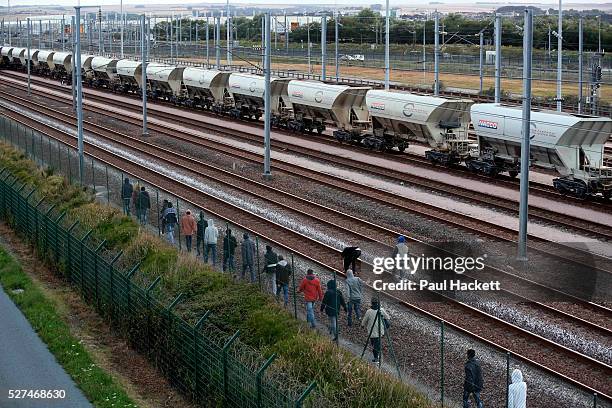 Migrants walk along the railway track leading to the EuroTunnel at night, in Calais, France, August 10, 2015. Migrants are attempting to enter the...