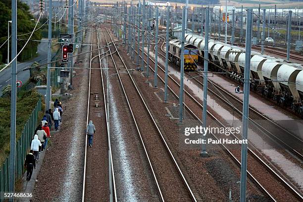 Migrants walk along the railway track leading to the EuroTunnel at night, in Calais, France, August 10, 2015. Migrants are attempting to enter the...