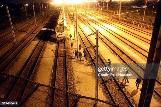Migrants walk along the railway track leading to the EuroTunnel at night, in Calais, France, August 10, 2015. Migrants are attempting to enter the...