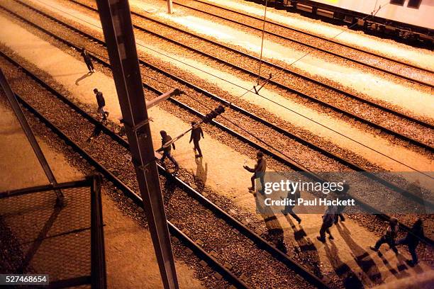Migrants walk along the railway track leading to the EuroTunnel at night, in Calais, France, August 10, 2015. Migrants are attempting to enter the...