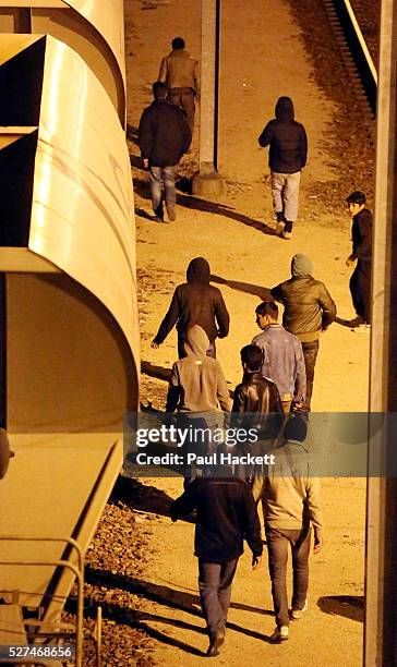 Migrants walk along the railway track leading to the EuroTunnel at night, in Calais, France, August 10, 2015. Migrants are attempting to enter the...