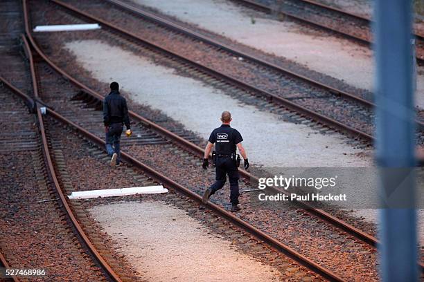 Migrants walk along the railway track leading to the EuroTunnel at night, in Calais, France, August 10, 2015. Migrants are attempting to enter the...