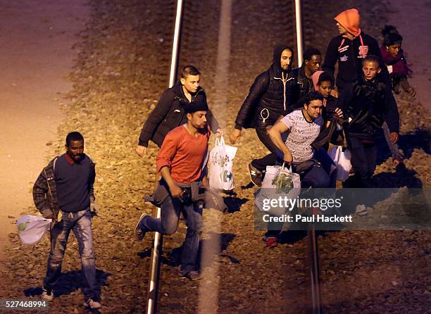 Migrants walk along the railway track leading to the EuroTunnel at night, in Calais, France, August 10, 2015. Migrants are attempting to enter the...
