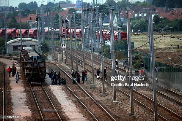 Migrants walk along the railway track leading to the EuroTunnel at night, in Calais, France, August 10, 2015. Migrants are attempting to enter the...