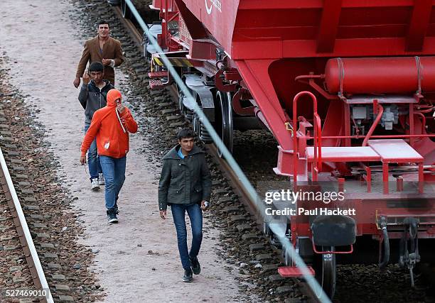 Migrants walk along the railway track leading to the EuroTunnel at night, in Calais, France, August 10, 2015. Migrants are attempting to enter the...