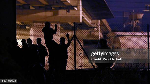 Migrants walk along the railway track leading to the EuroTunnel at night, in Calais, France, August 10, 2015. Migrants are attempting to enter the...