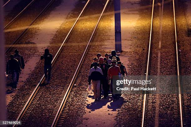 Migrants walk along the railway track leading to the EuroTunnel at night, in Calais, France, August 10, 2015. Migrants are attempting to enter the...