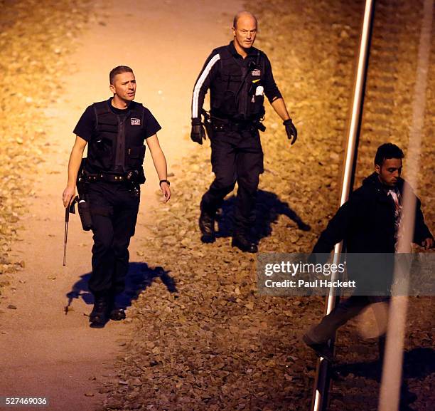 Migrants walk along the railway track leading to the EuroTunnel at night, in Calais, France, August 10, 2015. Migrants are attempting to enter the...