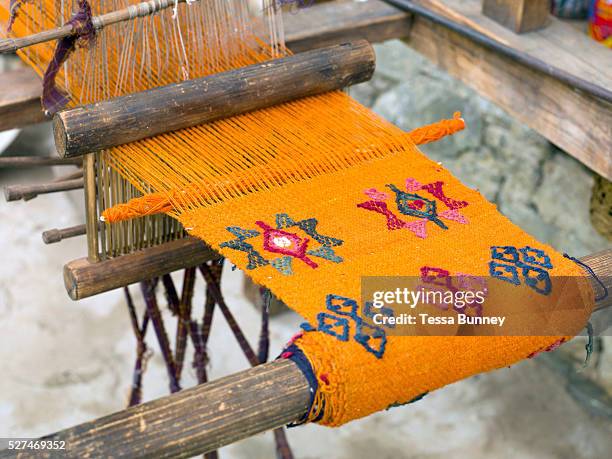 Handwoven woollen yathra skarf on a Tibetan style loom outside her farmhouse in the Tang Valley, Bumthang, Central Bhutan. Yathra is a hand woven...