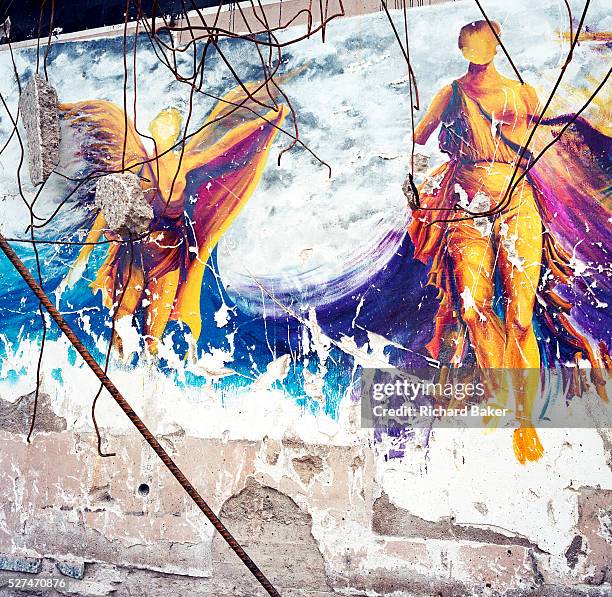 On a partially-demolished building, a mural of the ancient Goddess Nike remains chipped and scraped on an old restaurant wall. Nike was the Goddess...