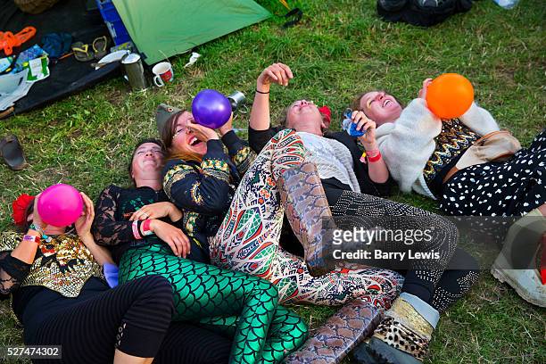 Glastonbury Festival, 2015. Group of girls all dressed up inhaling baloons of nitrous oxide, or laughing gas, in the camping grounds before the big...