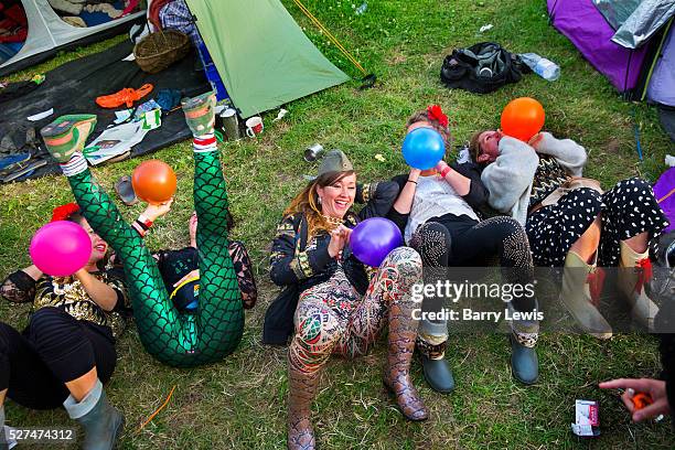 Glastonbury Festival, 2015. Group of girls all dressed up inhaling baloons of nitrous oxide, or laughing gas, in the camping grounds before the big...