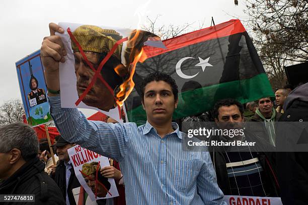 Libyan exile burns a picture of dictator Colonel Gaddafi during protests opposite London Libyan embassy during the country?s 2011 uprising. Holding...