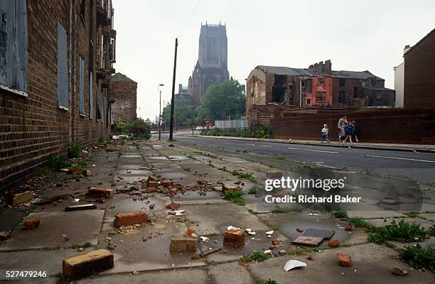 Low, wide landscape of dereliction and poverty during the early 1990s in the city of Liverpool, England. The Catholic cathedral rises high in the...