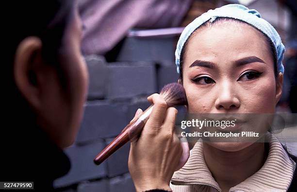 Zhang Lin, 23 leading Yue opera performer from the Xiao Bai Hua Shaoxing Opera Troupe having her make-up applied before a performance in a rural...