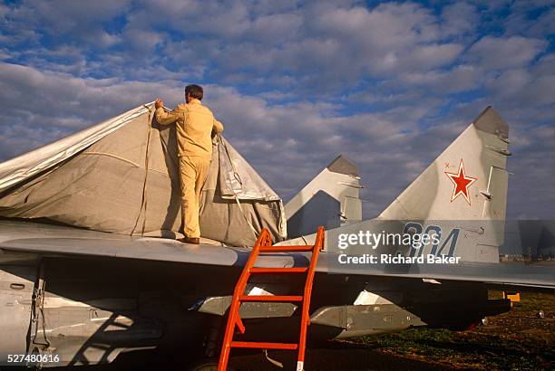 Migoyan technician covers a Mikoyan MiG-29 fighter jet as it makes its first ever display appearance to a western air show audience. The Mikoyan...