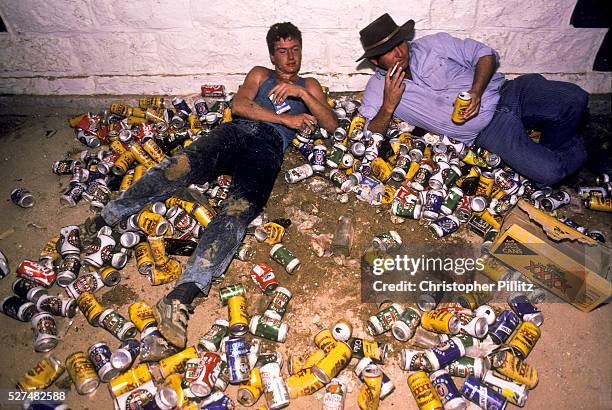 Drunk men lying amidst empty beer cans, during the annual Birdsville races which attracts thousands of party going beer swilling, men from all over...