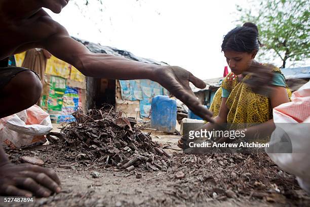 Tehkhand Slum, Delhi , India. A woman sorts through the scrap metal she and her family have collected from the streets and rubbish tips to sell to...