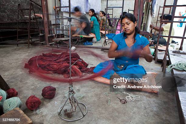 Nepalese female worker of the R.C Rug Factory in the Narayanthan area of Kathmandu, Nepal. She is using a spinning device to wrap the wool up into...