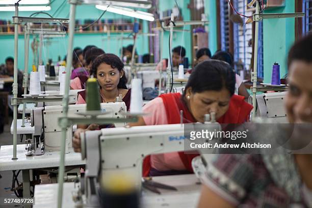 Nepalese factory worker looks away from her work and listens to her colleagues talking at Surijha Traders garment factory in Kathmandu, Nepal. The...
