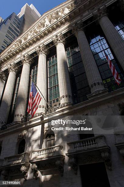Classical pillars and American flag hanging in front of the New York Stock Exchange on Wall Street, Lower Manhattan. This famous street symbolises...