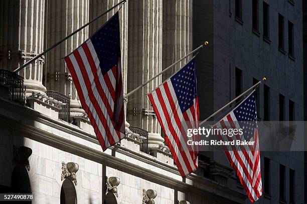 Classical pillars and American flag hanging in front of the New York Stock Exchange on Wall Street, Lower Manhattan. This famous street symbolises...
