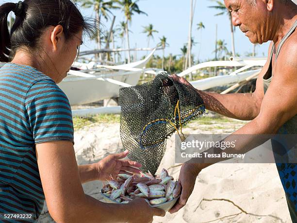 Imelda Esgana, fish vendor discussing the day's catch with a fisherman, Talisay, Santa Fe, Bantayan Island, The Philippines. Every morning at 7 am...