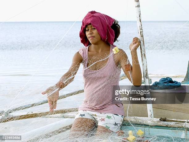 Noveline Pinote , the pregnant wife of a fisherman prepares the fishing nets on her husbands pump boat, Pooc, Bantayan Island, The Philippines. On...