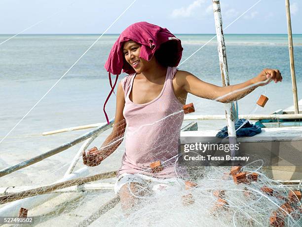 Noveline Pinote , the pregnant wife of a fisherman prepares the fishing nets on her husbands pump boat, Pooc, Bantayan Island, The Philippines. On...
