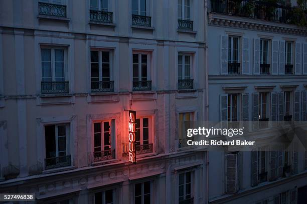 Neon sign outside the Amour Hotel at 8 rue Navarin, 9th Arrondissement, Paris, France. Seen from another hotel on the same street, we see the glow of...