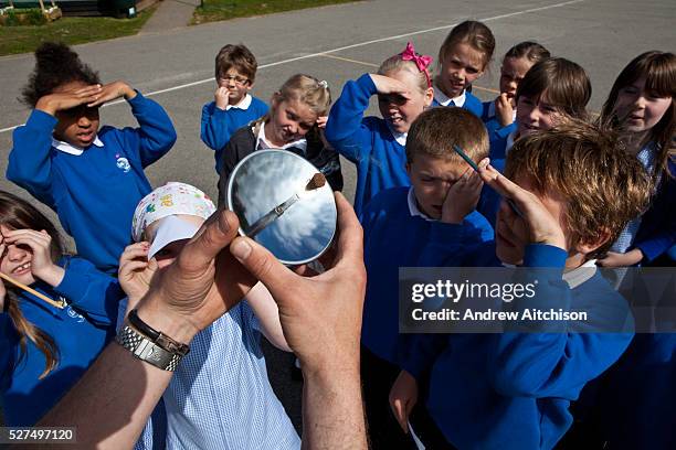 Primary school children watch a Sundance solar spark lighter in action in the school playground. The device is designed to focus the sun?s radiant...