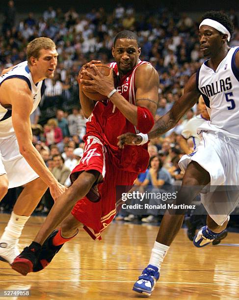 Tracy McGrady of the Houston Rockets moves the ball past Dirk Nowitzki and Josh Howard of the Dallas Mavericks in Game five of the Western Conference...