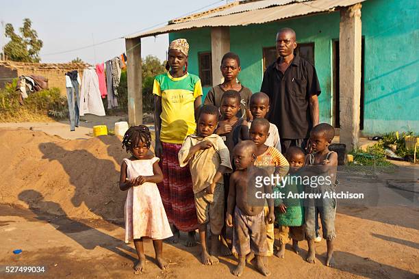 African family stands outside their green home in a compound on Chimoio, Manica District, Mozambique. The man and woman are the biological parents to...
