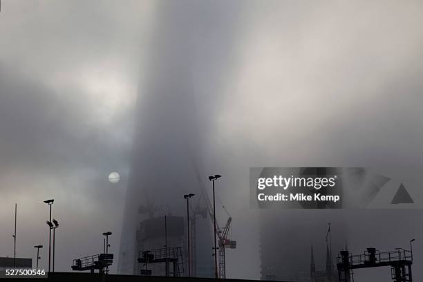 Thick fog over London obscures The Shard which is under construction at London Bridge making a peaceful yet eerie landscape atmosphere as towers...