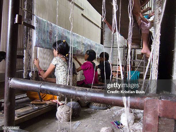 The girl in pink is thought to be a minor at work. The carpet factories are small and cramped and can be found in small buildings and ware houses...