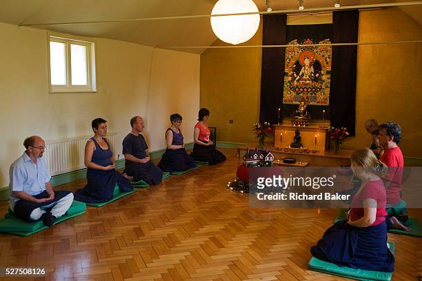 Buddhists meditate in silence for 30 minutes in their Shrine Room at the Rivendell Buddhist Retreat Centre, England. A middle-aged man and a younger...