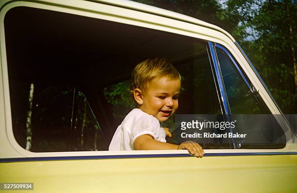 Young boy stands up in his father's Anglia car on a summer day out in the early nineteen sixties. Standing up on the driver's front seat the child...