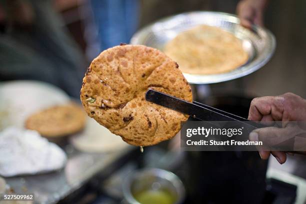 Fried paratha at the famous Parawthe Walla in Old Delhi, India. The parantha is an Indian fried bread, folded and filled with fillings and then...