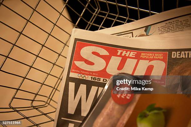 The Sun newspaper in a shopping basket in London, England, UK. British police arrested five senior members of staff at News Corporation's newspaper...