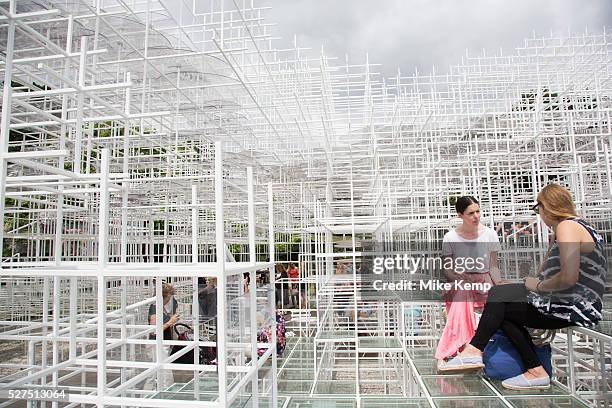 People enjoying climbing up the Serpentine Pavilion 2013 by Japanese architect, Sou Fujimoto. London, England, UK. He is the thirteenth and, at 41,...