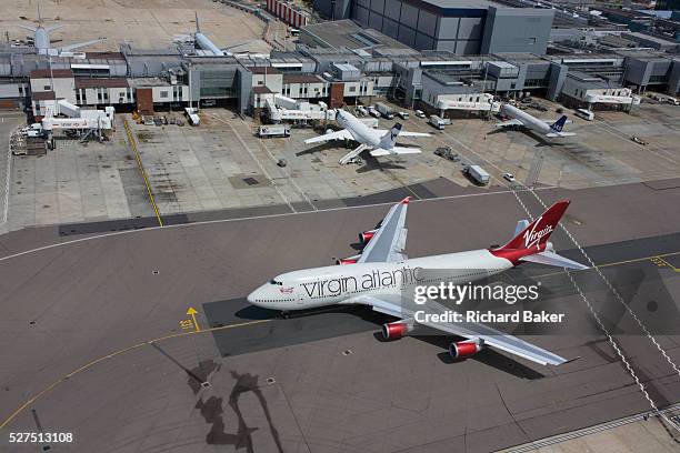 Aerial view of Virgin Atlantic airliner's wing and engine at London Heathrow airport. Taxiing along the centreline that helps pilots navigate to...