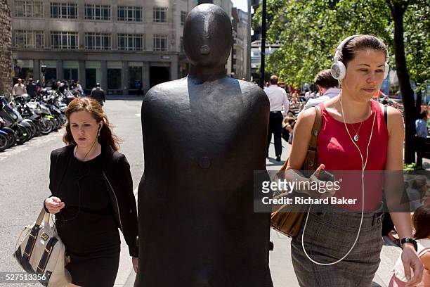 City of London office workers pass one of a pair of leaning figures by Anthony Gormley entitled Parralel Field , part of Sculpture in the City, a...