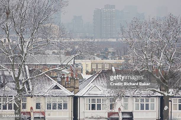 Snow covered rooftops of south London residential houses, some with adequate heat proofing and others poorly insulated. In the distance are the...