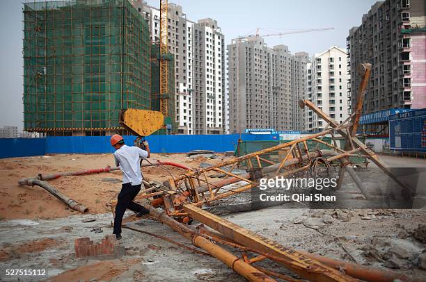 Worker hoist construction equipment onto the cables of a crane on the site of a new apartment development on the outskirts of Yulin, Shaanxi...