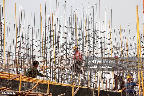 Workers use wires and steel rebars to build the skeleton of a building on the site of a new apartment development on the outskirts of Yulin, Shaanxi...