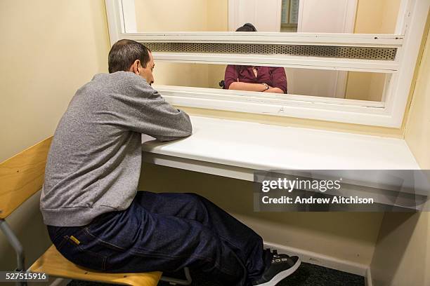 Prisoner on a closed visit sits talking to his wife. Closed visits take place in locked rooms with a toughened glass window between the prisoner and...