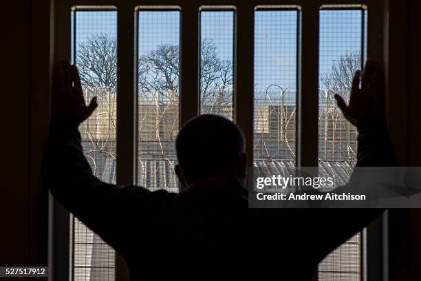 Prisoner staring out of a window down one of the corridors of the enhanced wing at HMP/YOI Portland, Dorset, United Kingdom.