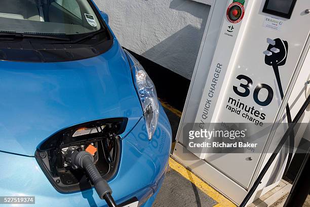 Fast charging a Nissan Leaf electric car at an electrical charging point offering an EV 30 minute charge. The Nissan Leaf is a five-door hatchback...