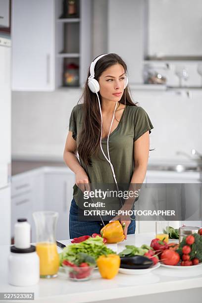 woman with headphones cutting bell pepper - mp3 juices stock pictures, royalty-free photos & images