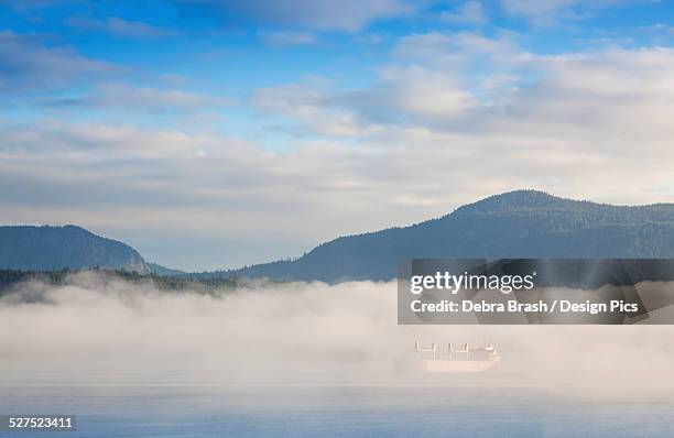 fog surrounds a freighter anchored in cowichan bay off vancouver island - cowichan bay stock pictures, royalty-free photos & images